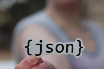 A {json} sticker held between two fingers